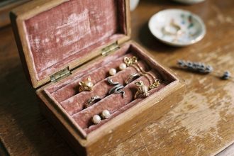 Boîte à bijoux vintage en velours rose avec des bagues en forme d'animaux — renard, serpent et hibou — posées sur un tissu doux