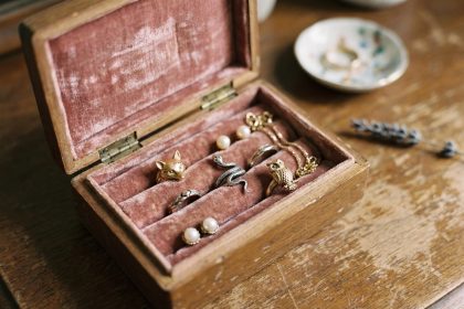 Boîte à bijoux vintage en velours rose avec des bagues en forme d'animaux — renard, serpent et hibou — posées sur un tissu doux