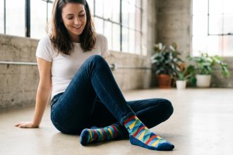 Femme assise en jeans basique portant des chaussettes fantaisie géométriques colorées dans un loft urbain minimaliste
