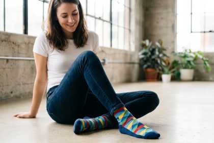 Femme assise en jeans basique portant des chaussettes fantaisie géométriques colorées dans un loft urbain minimaliste