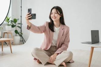 Jeune influenceuse coréenne filmant du contenu dans un studio minimaliste à Séoul, tenant son smartphone avec un sourire naturel